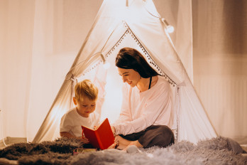 mother-with-son-sitting-cozy-tent-with-lights-home-christmas